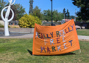 Really Really Free Market banner An orange fabric banner with the words "Really Really Free Market" made from different colored fabrics